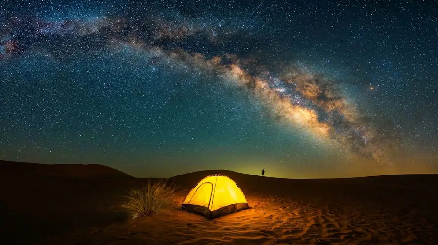 Glowing camping tent under a sweeping arch of the Milky Way galaxy in the quiet Abu Dhabi desert.