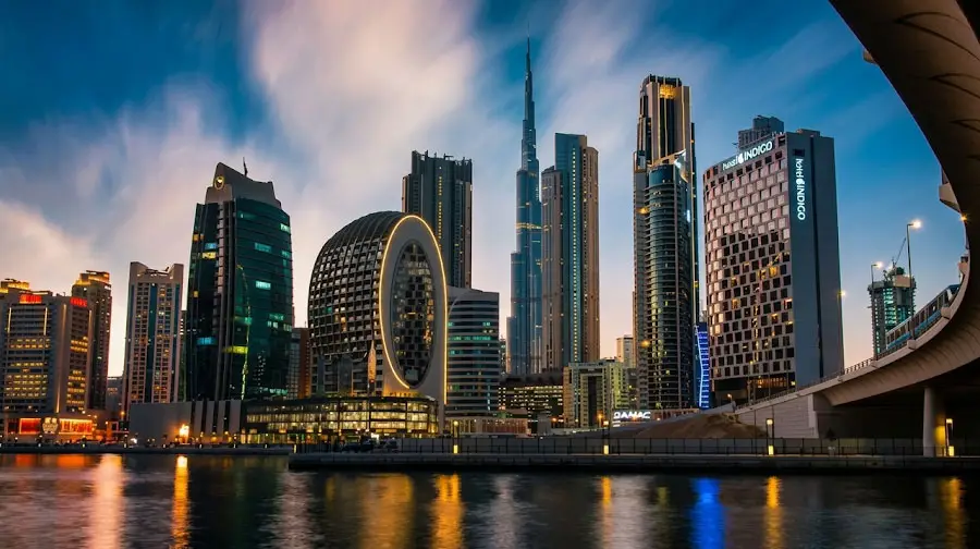 Modern Downtown Dubai skyline at dusk featuring illuminated skyscrapers and the Burj Khalifa reflecting on Business Bay water.