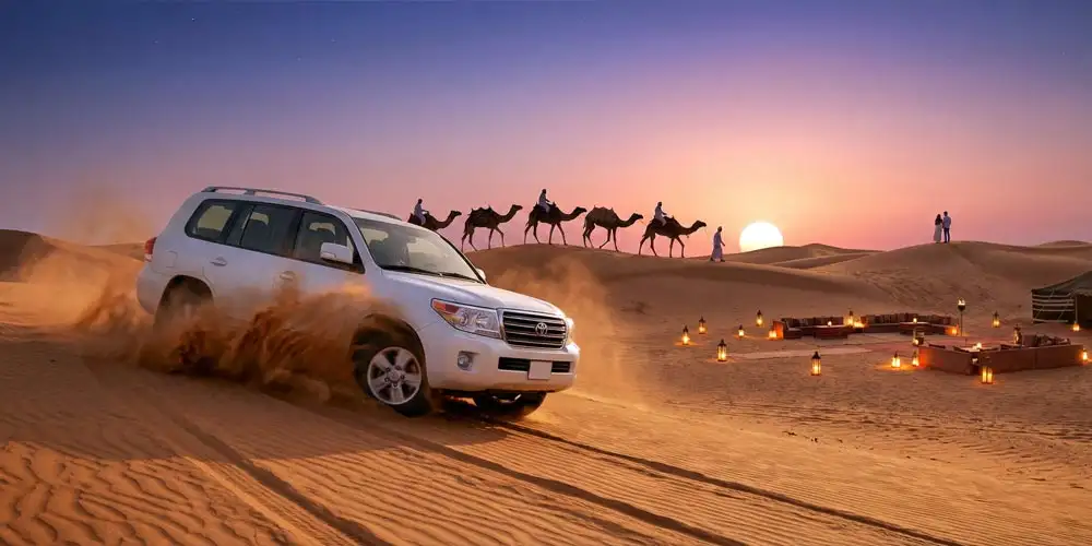 A white 4x4 vehicle kicks up sand during an Evening Desert Safari Abu Dhabi Dune Bashing and Camel Ride, with a line of camels on a ridge and a vibrant sunset glowing over the desert dunes in the background.