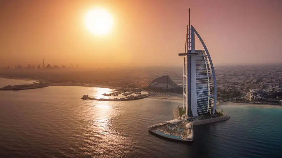 Aerial view of the sail-shaped Burj Al Arab hotel surrounded by the Persian Gulf waters during sunset in Dubai.