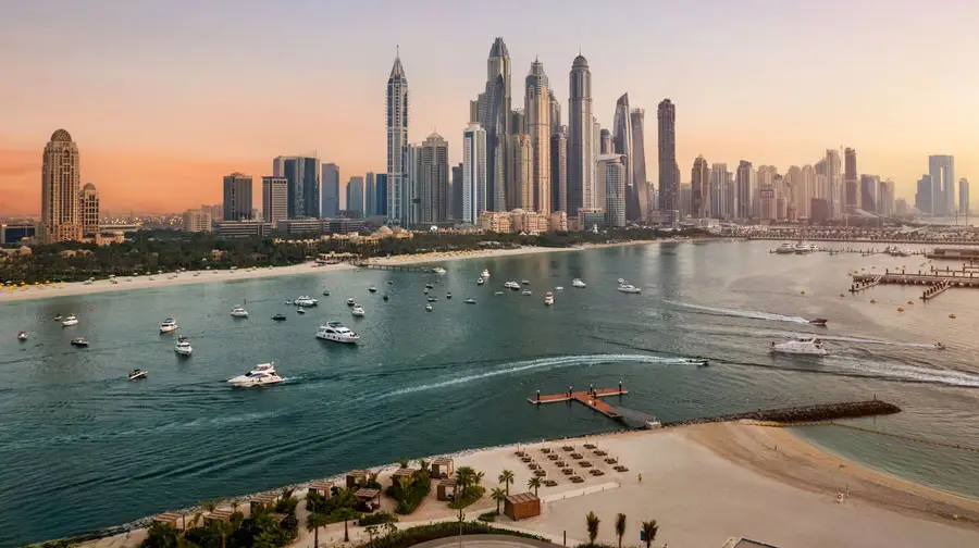 High-angle view of yachts navigating the waters off Dubai Marina lined with modern high-rise skyscrapers.